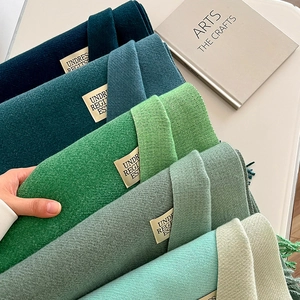 Detail of green pashmina scarves in five gradients with fine twill weave and fringe edges