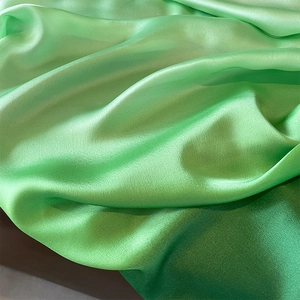 Detail of high-quality bright green satin fabric showing fine texture and pearly luster