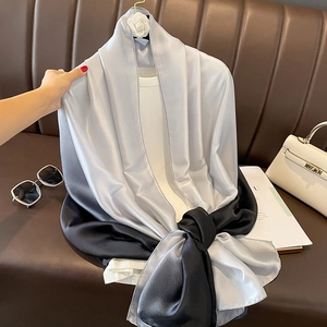 Detail of grey gradient satin scarf with camellia brooch on a leather surface