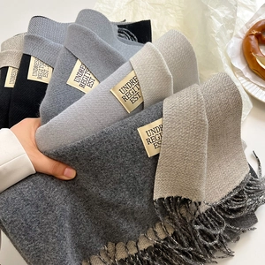 Stack of thick double-sided cashmere scarves in neutral tones with elegant tassels