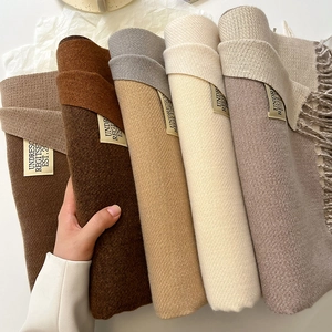 Detail showing the soft twill weave texture and elegant labels of various cashmere-like scarves