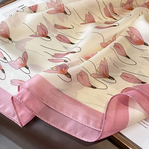 Detail view of elegant floral silk scarf with pink borders and smooth pearl luster