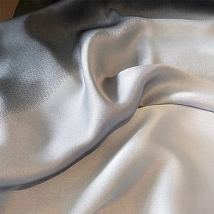 Macro shot of gradient silk scarf fabric showing smooth silver to grey texture