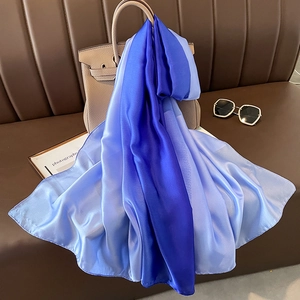 Detail of gradient blue satin scarf draped elegantly over a luxury leather handbag