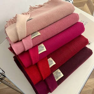 Close-up of double-sided cashmere-like scarves with fringe and brand label details