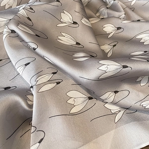 Macro detail of silky grey fabric featuring elegant white floral prints and soft draping
