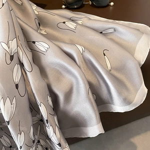 Close-up of silver-grey silk scarf with white floral print and smooth texture