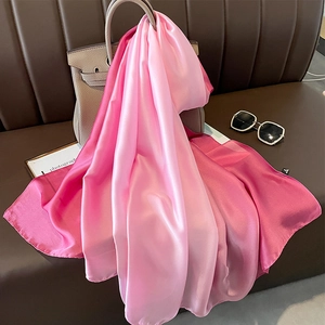 Close-up of pink gradient satin scarf draped on handbag showing silky smooth texture