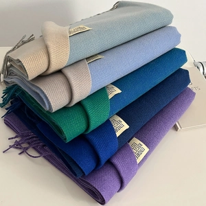 Detail view of multicolored cashmere-like scarves with fringe and woven labels