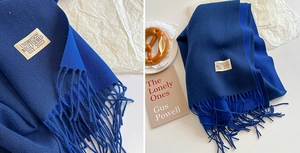 Detail of royal blue scarf with soft fringe edges and minimalist brand fabric label