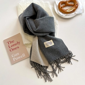 Detail of double-sided cashmere scarf showing soft texture, fringes and logo label