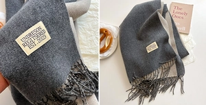 Close-up of double-sided gray cashmere-like scarf with fringe detail and woven label