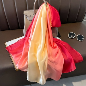 Macro detail of gradient satin silk scarf draped over a classic leather handbag