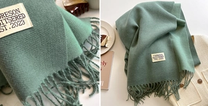Macro detail of sage green knit scarf with long tassels and stitched fabric label