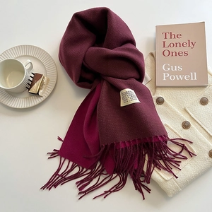 Detail of burgundy cashmere feel scarf showing twill texture, tassels, and chic accessories