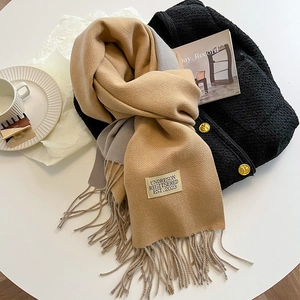 Detail of beige and grey double-sided cashmere-like scarf with tassels on tweed coat
