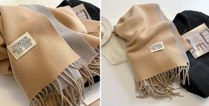 Detail of two-tone camel and grey cashmere-like scarf with fringe and brand label