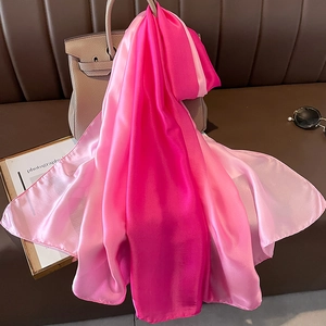 Detail of pink gradient satin silk scarf draped over a classic leather handbag