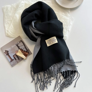 Detail of double-sided cashmere-like scarf with fringe and woven label in a lifestyle setting