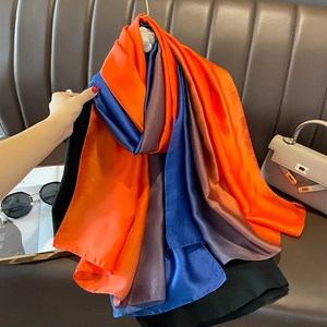 Detailed texture of gradient satin silk scarf with vibrant orange and blue panel colors