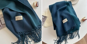 Detail of double-sided knit scarf featuring navy and green tones with fringe and brand label