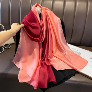 Detail of gradient satin scarf with camellia clip on a luxury leather background