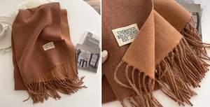 Macro shot of dark brown cashmere-like scarf texture with fringe and brand label