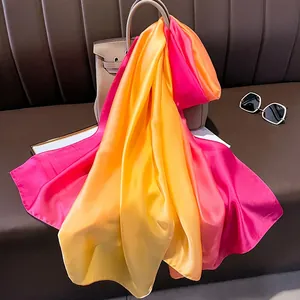 Detail of gradient satin silk scarf draped on a leather bag with high gloss finish
