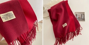 Detail of red tassel scarf showing dual-tone knit texture and a woven label accent