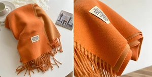 Detailed close-up of orange cashmere-like scarf showing soft texture and long tassels
