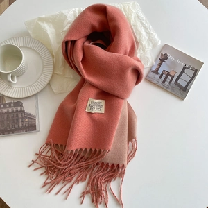 Detail of coral pink knit scarf with soft cashmere-like texture and fringed edges
