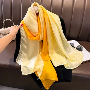 Detail of elegant yellow gradient satin scarf with smooth silk texture on dark background