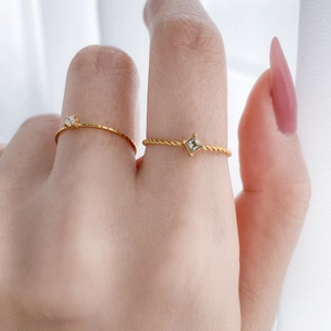 Close-up of gold titanium steel rings with square zircon and twisted rope texture