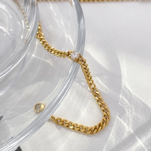 Detail of 18K gold plated titanium chain with sparkling cubic zirconia on glass edge
