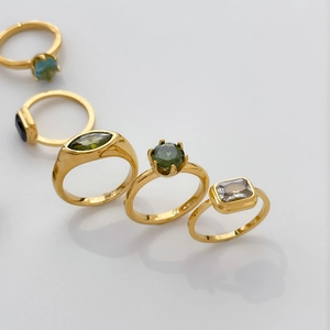 Gros plan de bagues plaquées or 18K avec pierres colorées taille marquise et émeraude