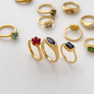Gros plan de bagues plaquées or 18 carats avec pierres précieuses colorées de formes variées
