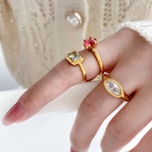 Détail de trois bagues plaquées or 18K avec des pierres de zircone rouges et transparentes