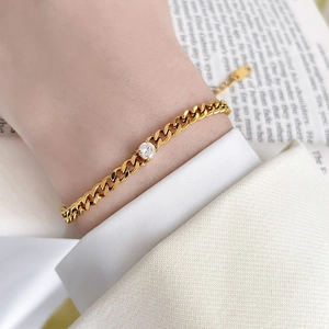 Detail of 18K gold-plated titanium chain bracelet with round zircon on a model's wrist