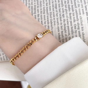 Detail of 18K gold plated titanium bracelet with a sparkling square zircon on Cuban chain
