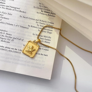 Macro detail of golden rectangular pendant with angel relief on a vintage book page