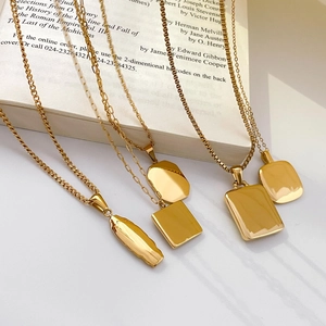 Detail of assorted geometric gold-plated titanium necklaces on an open book background