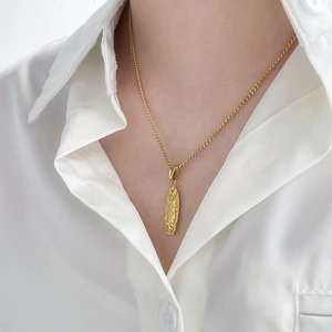 Gold Virgin Mary oval medallion necklace in polished steel worn on a white shirt