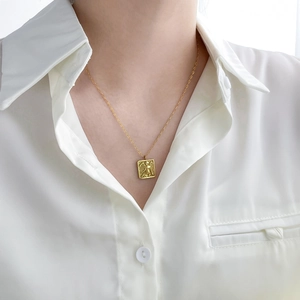 Macro view of vintage gold-plated square pendant with angel relief on a fine chain