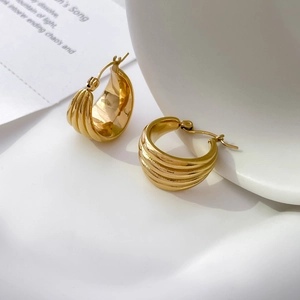 Detail view of 18K gold plated tiered wavy hoop earrings on a minimalist white backdrop
