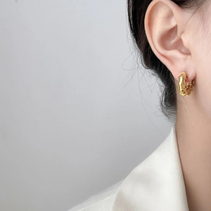 Detail of 18K gold-plated multi-layer textured hoop earrings on a female model