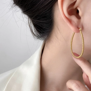 Detailed view of gold beaded oval hoop earring worn on model for elegant styling