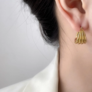 Close-up of ribbed multi-layer gold earrings on model showing textured shell design
