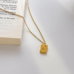 Macro detail of gold-plated rectangle star pendant necklace on a book edge