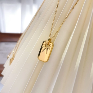 Detailed view of an 18K gold-plated rectangle pendant with radiant starburst engraving