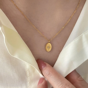 Elegant 18K gold plated titanium necklace with oval star pendant worn by a model